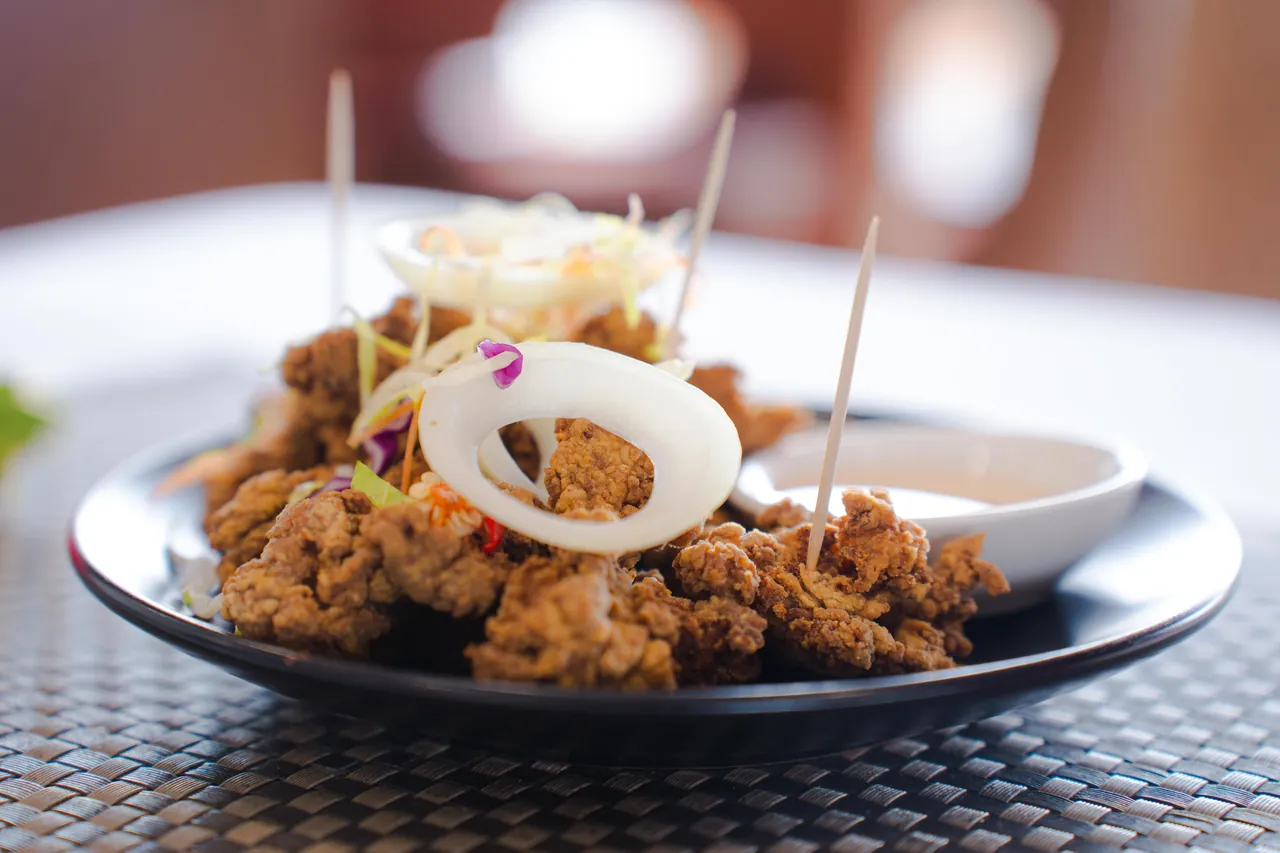 A crispy sharing plate with onion, slaw and dipping sauce