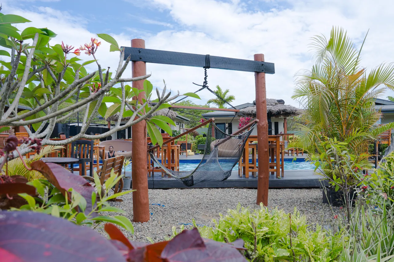 A hammock on a timber frame surrounded by tropical planting