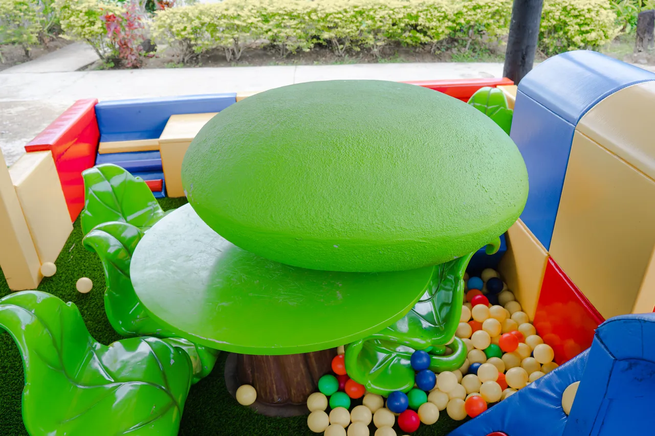 A green mushroom-shaped seat surrounded by colourful balls and soft play walls