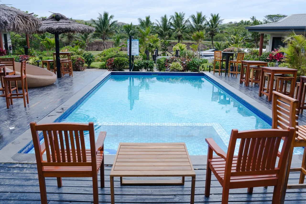 The outdoor pool framed by timber seating and tropical gardens