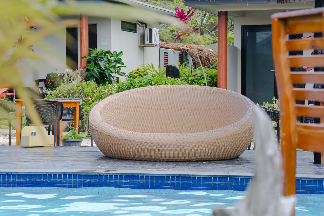 A round woven lounge beside the pool