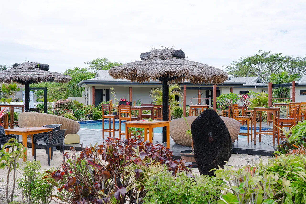 Poolside tables and thatched shade among the gardens